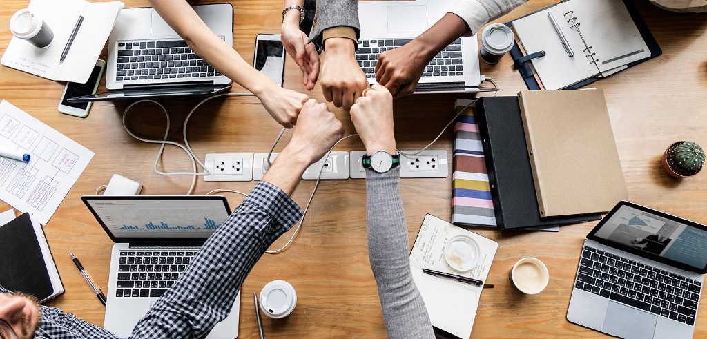 Pessoas de uma equipe se comprimentando em uma reunião de escritório